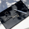 Image of Signature Eyelash Curler and Precision Tweezers laying on top of a black bag with the RevitaLash logo
