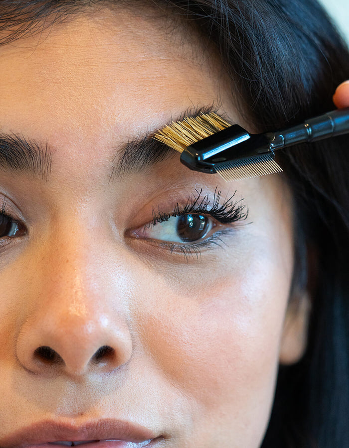 Person grooming eyebrows with a brush 