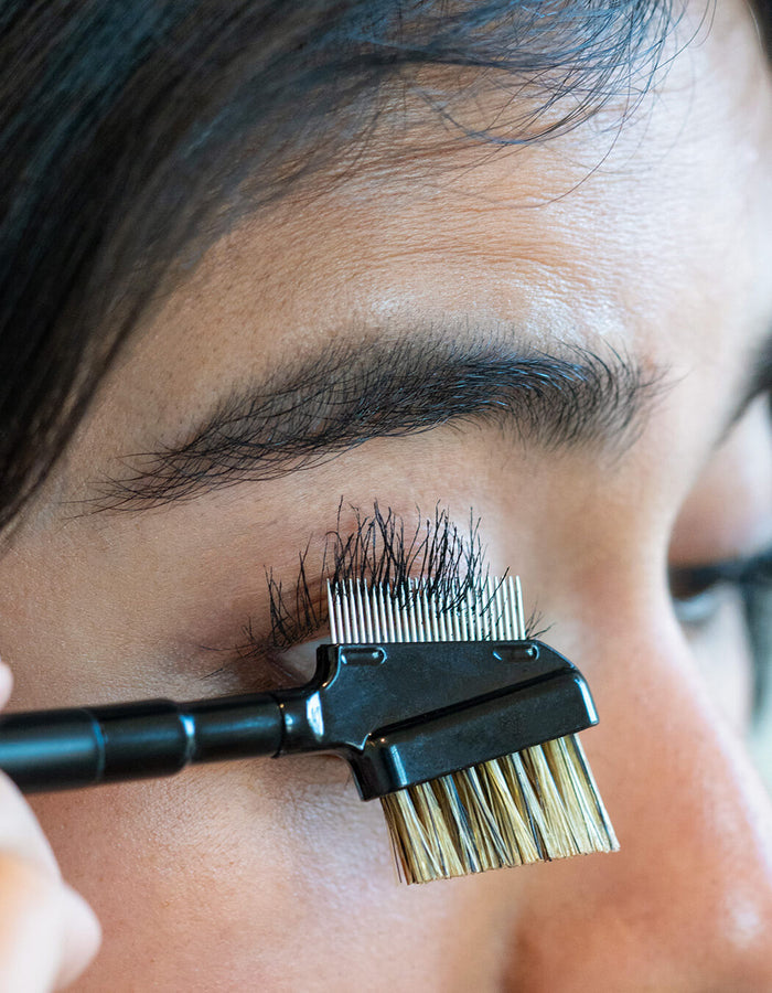 Person using a lash tool to comb their eyelashes